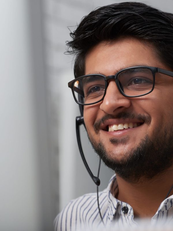 Face of cheerful Indian consulting service manager talking client via headset